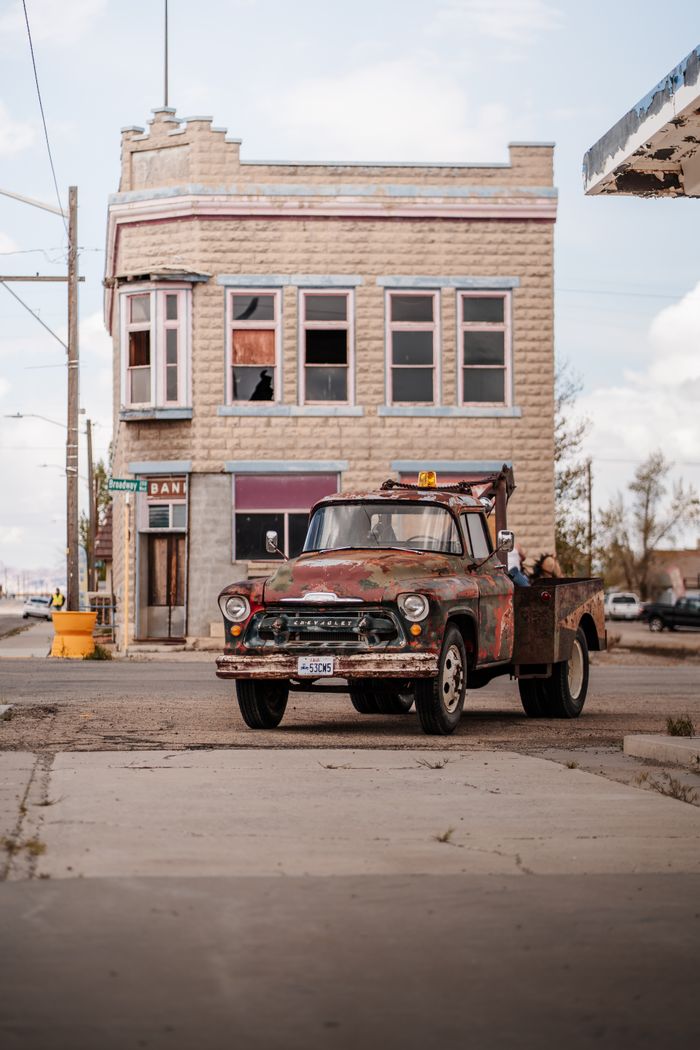 A vintage tow truck parked on a deserted street in front of an abandoned building in Utah.